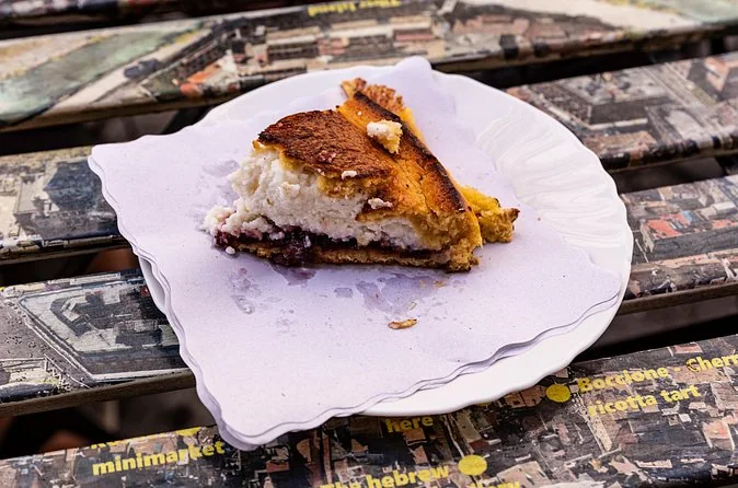 A slice of ricotta and cherry tart on a paper plate